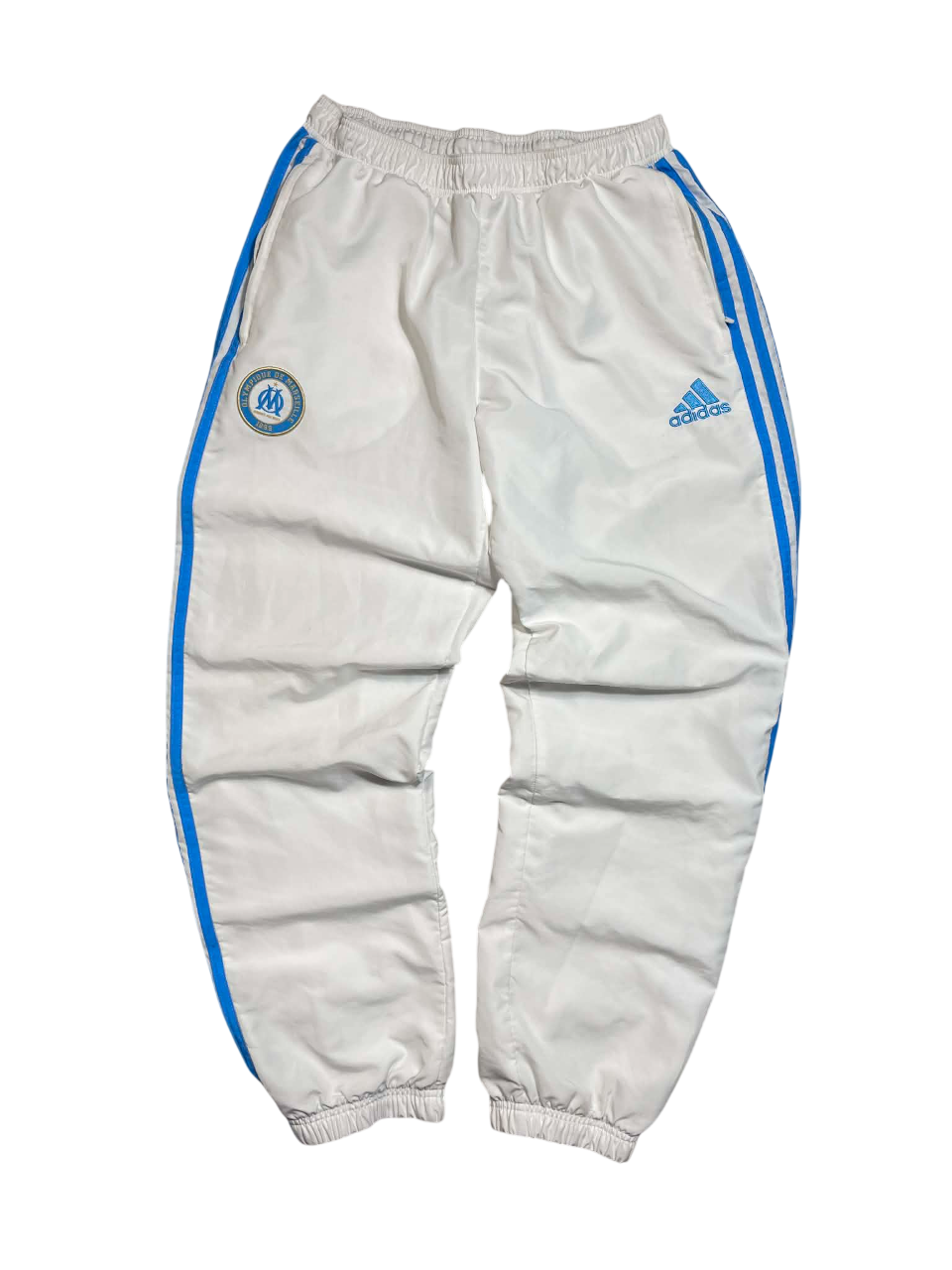 Fehér Adidas melegítő nadrág kék csíkokkal és Marseille logóval, vintage streetwear stílusban.