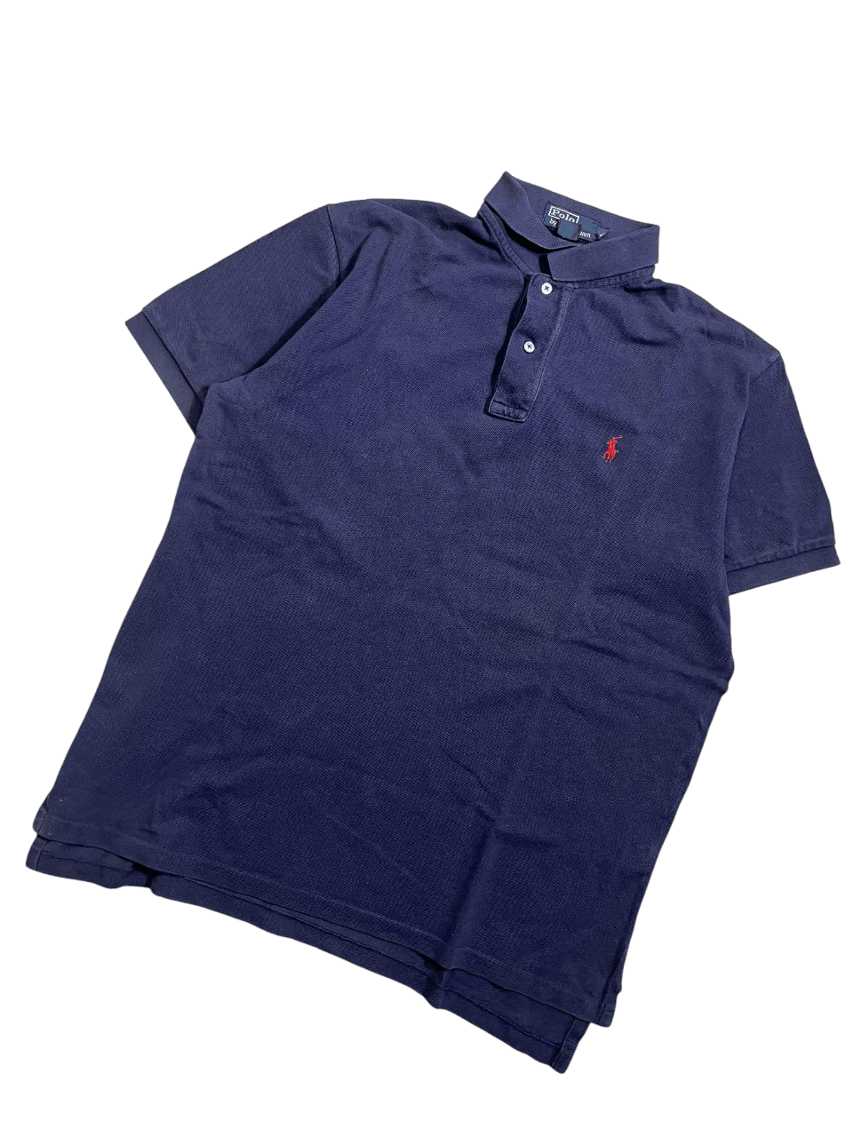 Sötétkék galléros póló, piros hímzett logóval, vintage streetwear stílusban.