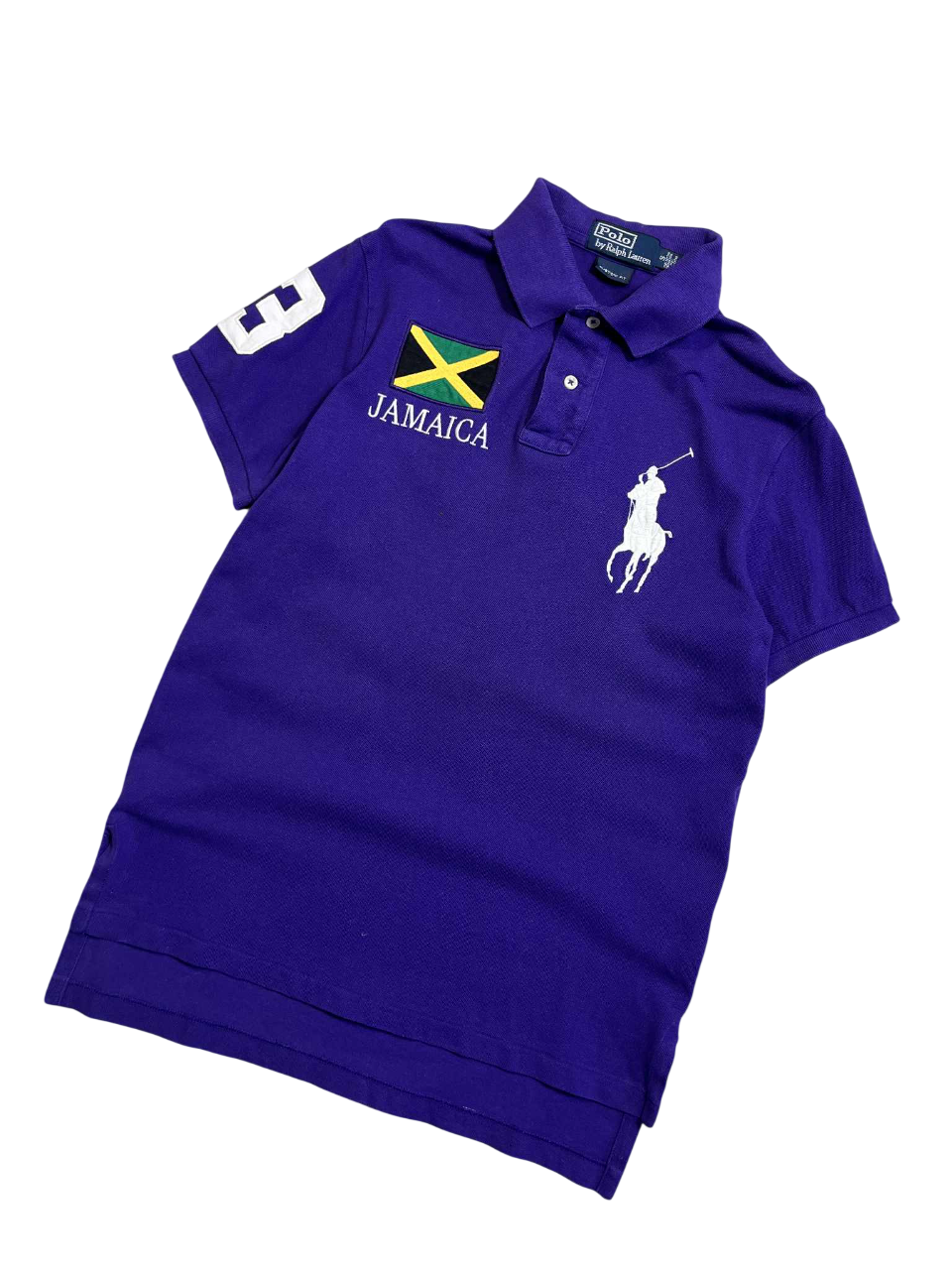 Lila Ralph Lauren Jamaica póló, bal felső részen zászlóval, hímzett logóval és számmal.