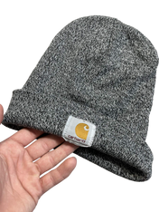 Szürke Carhartt kötött sapka kézben, streetwear stílus, márkajelzéssel az elején.